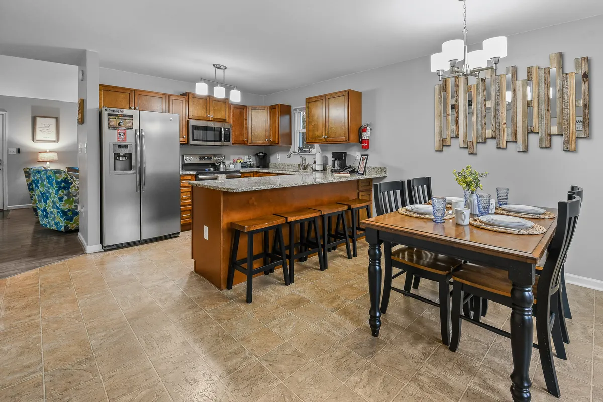 This image displays both the kitchen island with bar seating and a dining table arranged for a meal. The setup highlights the inviting atmosphere, with warm lighting and tasteful décor, and illustrates the transition between kitchen and dining spaces.