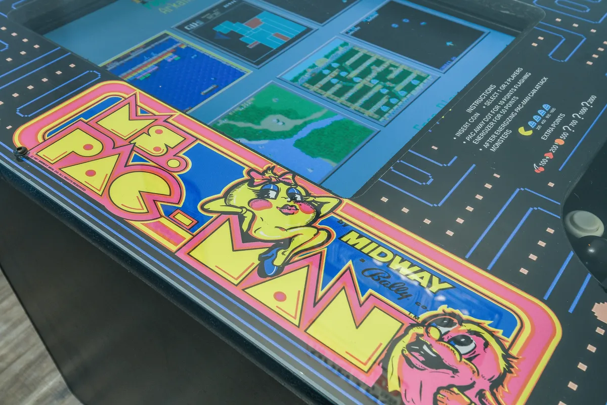 A playful interior scene featuring a Ms. Pac-Man arcade machine and a brightly lit game screen, evoking nostalgia and family fun within the home.