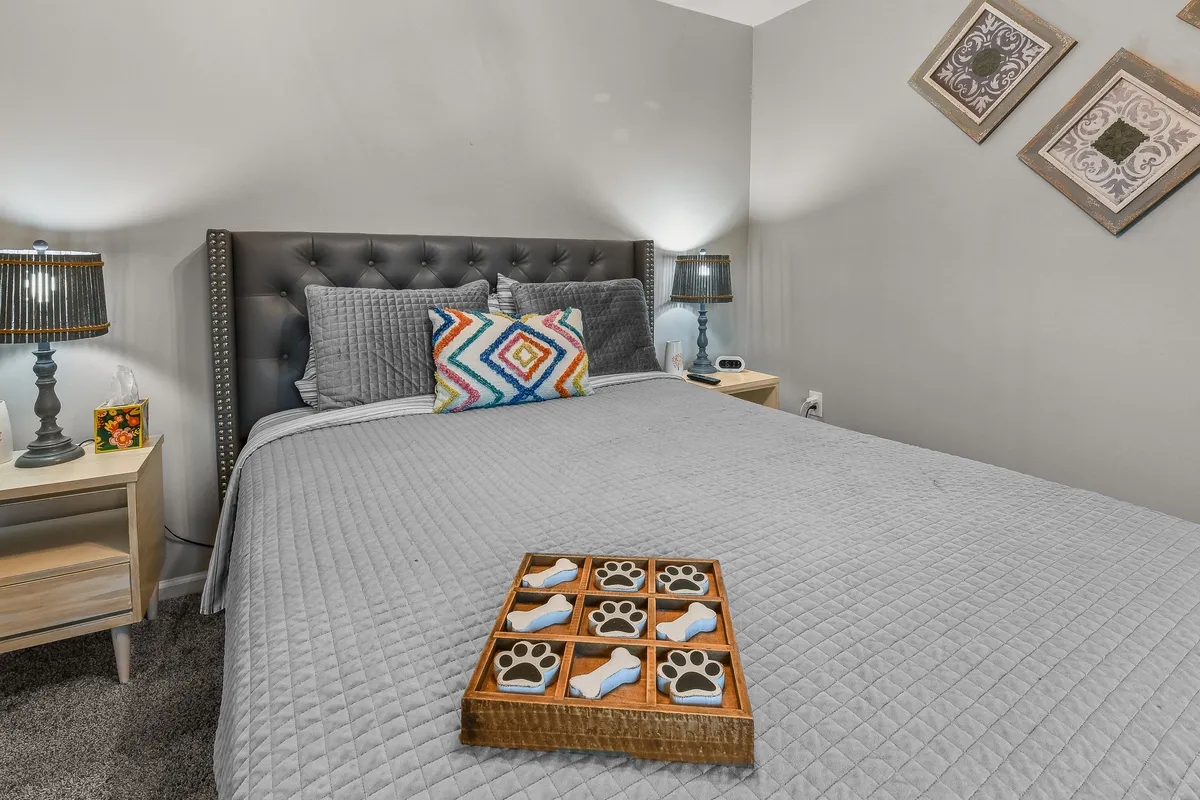 A cozy bedroom scene with a bed adorned with patterned pillows and a tray featuring pet-themed items. The decor suggests both comfort for guests and a playful, welcoming attitude toward pets.